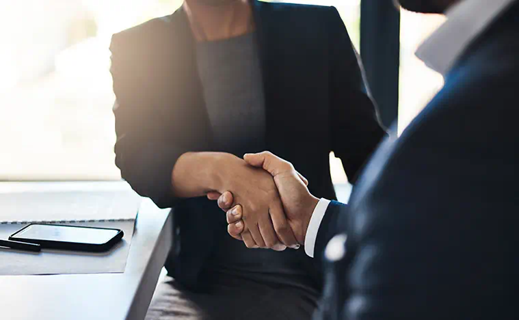 Make It Actionable Closeup shot of two unrecognizable businesspeople shaking hands in an office.