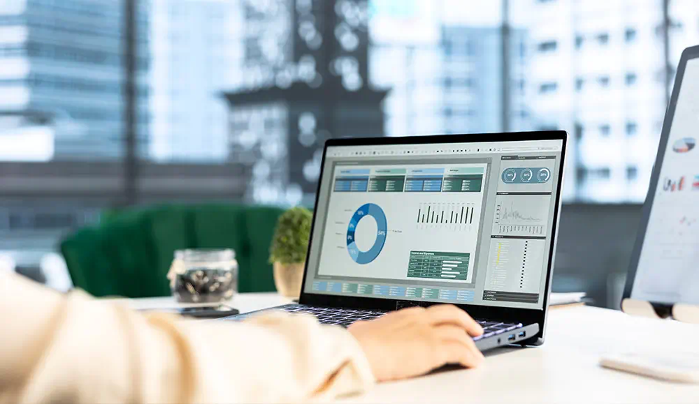 A business man typing on his laptop with graphs and charts showing.
