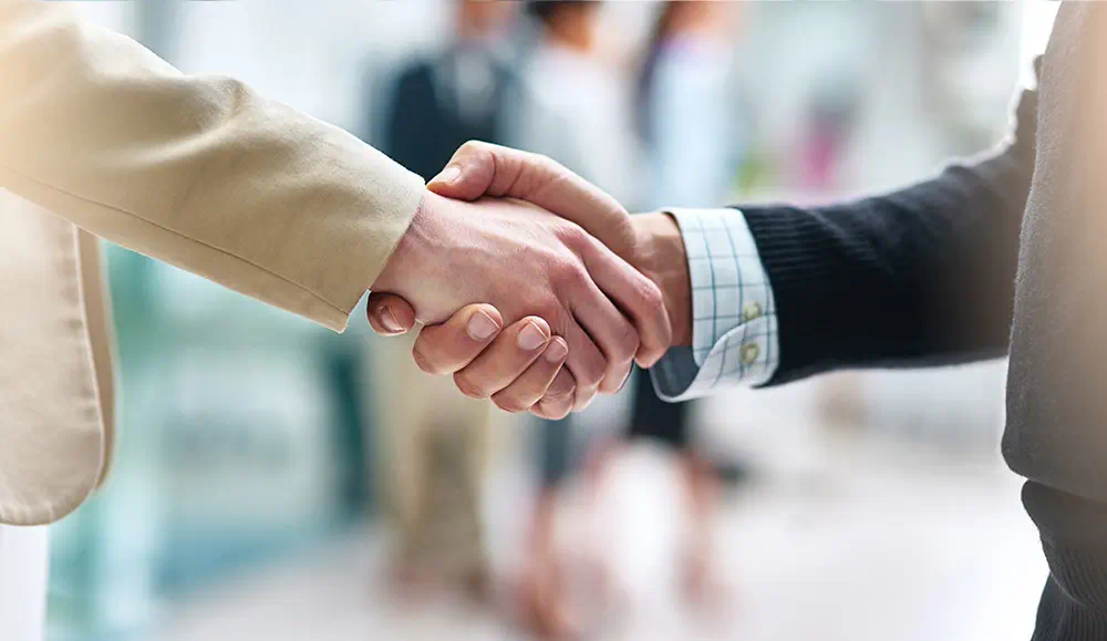 Two business men shaking hands in a business office space.