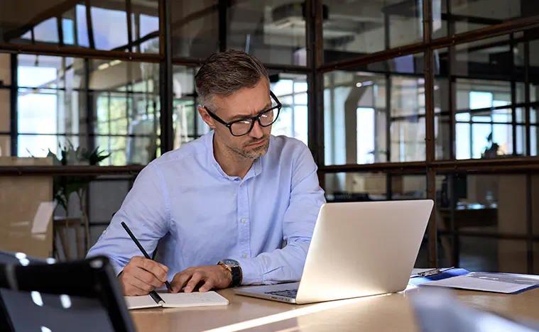 A business man works on his laptop in a modern office building.