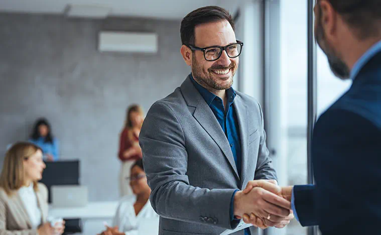 A young business man shakes the hand of his older collegue.