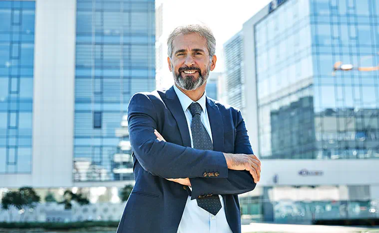 A business man posing in front of glass skyscrapers.