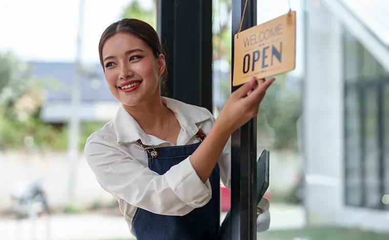 A woman turning over a sign to open in her new retail space.
