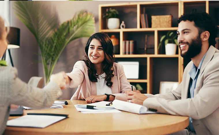 Lease Negotiation A business person shakes the hand of a client on the other side of a conference table.