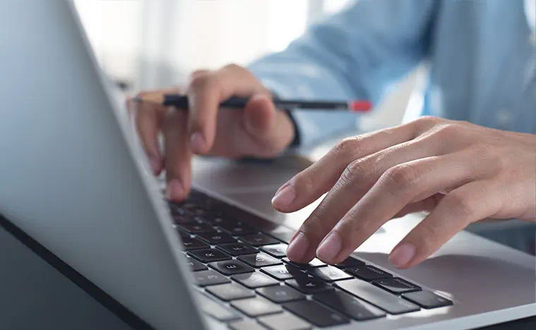 Market Search A business person types on a laptop in an office.