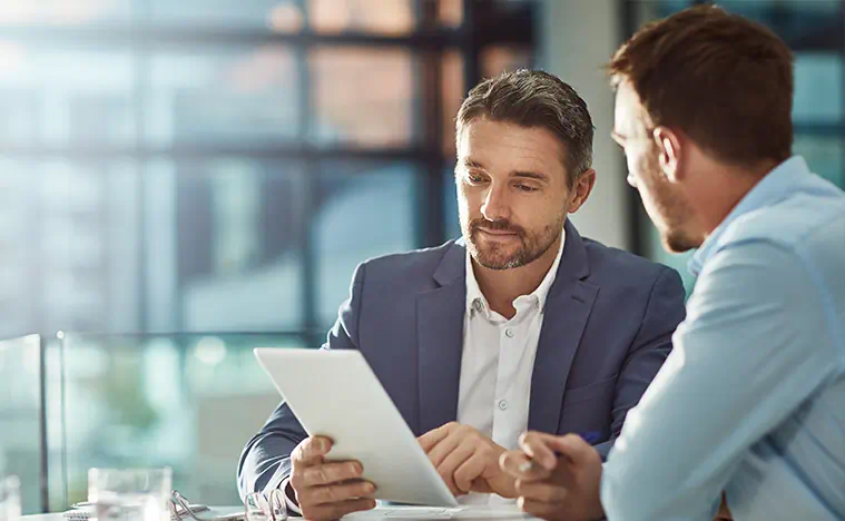 Two business men looking over a tablet in a professional office space.